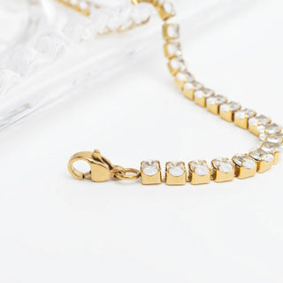 Gold bracelet with clear stones on a white background