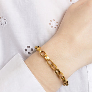 Gold chain bracelet on a wrist with a white lace background