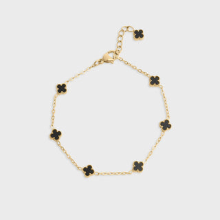 Gold bracelet with black floral-shaped charms on a light gray background