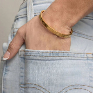 Gold bracelet on a wrist with denim jeans