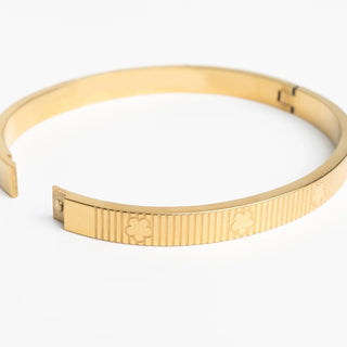 Gold bracelet with a textured tag on a white background