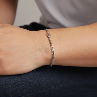 Silver bracelet on a wrist with a neutral background