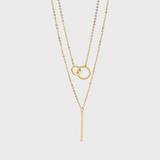 An Interlocked Circle and Bar Layered Charm gold necklaces on a light gray background