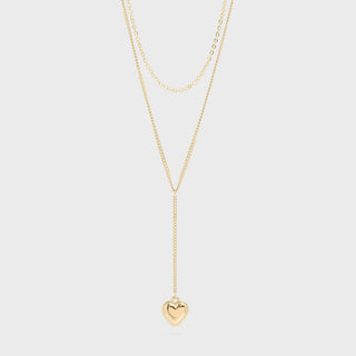 Gold necklace with a heart pendant on a light gray background