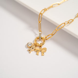 Gold bracelet with bow-shaped charms on a light background