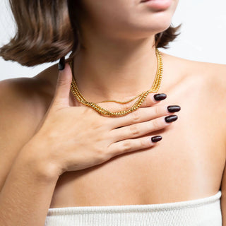Woman wearing a gold beaded necklace with a neutral background