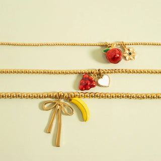 Gold beaded necklaces with colorful charms on a light green background