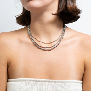 Woman wearing a silver beaded necklace on a plain background