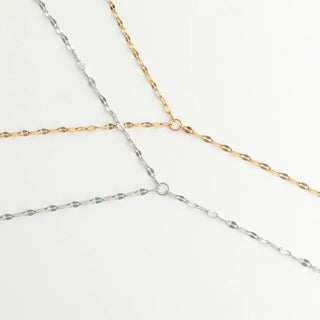 Three gold and silver Full Body Lip Chains intersecting on a light gray background