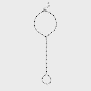 Silver hand chain with black and white beads on a light gray background