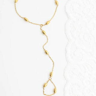 Gold Statement Bead Hand Chain with teardrop-shaped beads on a white background