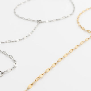 Two gold and silver Lip Hand Chains on a light gray background