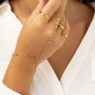 Gold Lip Hand Chain and rings on a hand against a white background