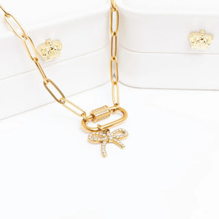 Gold necklace with bow charm on a white background