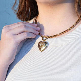 Person wearing a gold necklace with a heart-shaped pendant
