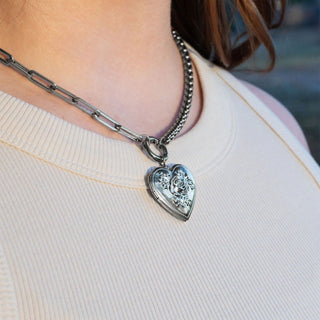 Silver heart-shaped pendant necklace on a person wearing a light-colored top.