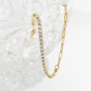 Gold bracelet with diamond accents on a textured white surface