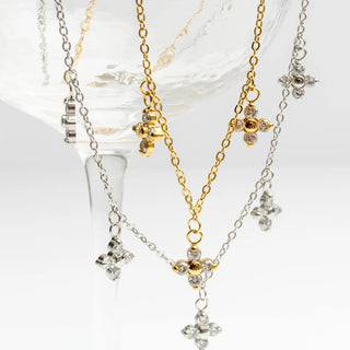 Three necklaces with floral pendants in gold, silver, and a mix of both on a white background.
