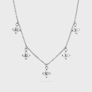 Silver necklace with floral pendants on a light gray background