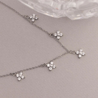 Silver necklace with floral pendants on a gray surface