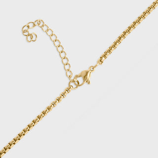 Gold chain necklace on a light gray background
