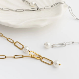 Gold and silver y-shaped chain necklaces with pearls on a white surface