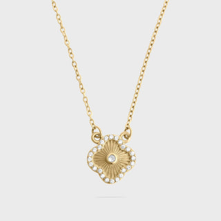 Gold necklace with a floral-shaped pendant on a light gray background