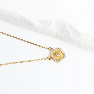 Gold necklace with a decorative pendant on a white background