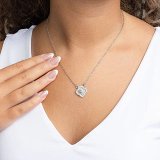 Necklace with a floral pendant worn by a person wearing a white top