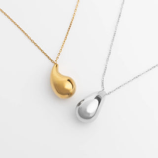 Gold and silver teardrop-shaped pendants on chains against a white background