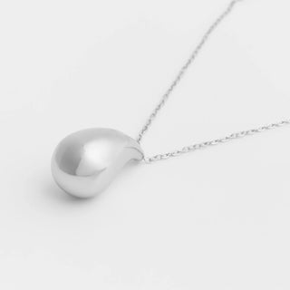 Silver necklace with a teardrop pendant on a light gray background