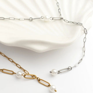 Two pearl necklaces, one gold and one silver, on a white background.