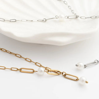 Gold and silver chain necklaces with pearls on a white surface