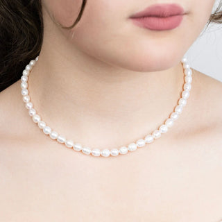 Pearl necklace worn by a person with a neutral background