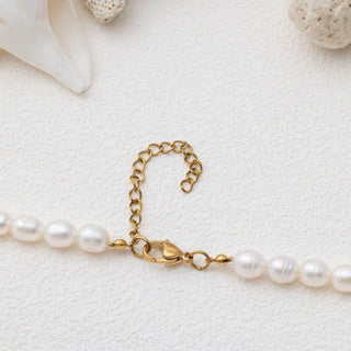 Pearl necklace with gold clasp on a light background