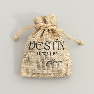 Jute drawstring bag with 'Destin Jewelry' branding on a gray background