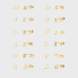 Set of gold earrings with zodiac symbols on a light gray background