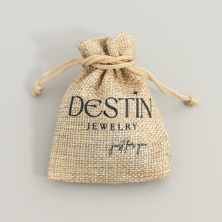 Jute drawstring bag with 'Destin Jewelry' branding on a light gray background
