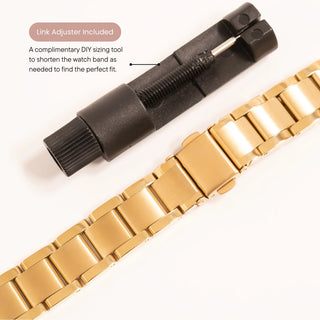 Gold watch band with black link adjuster on a white background