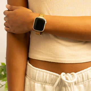 Person wearing a gold smartwatch on a blurred background