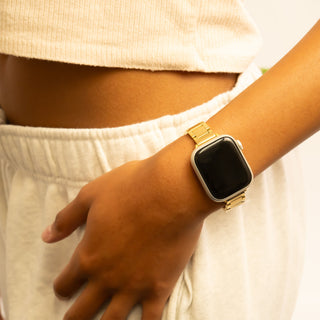 Person wearing a gold smartwatch on a plain background