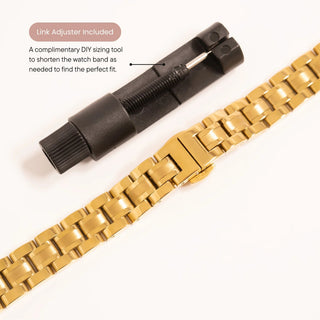 Gold watch band with black link adjuster on a white background
