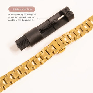 Gold watch band with black link adjuster on a white background