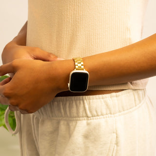 Person wearing a gold smartwatch on a blurred background