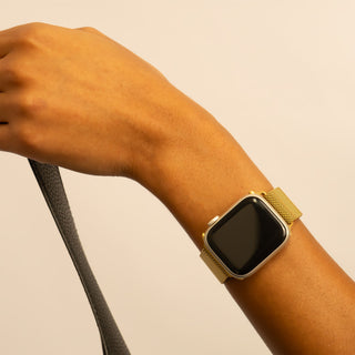 Gold smartwatch on a wrist with a beige background