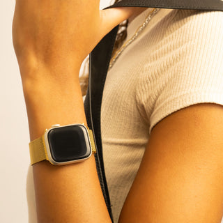 Person wearing a smartwatch with a yellow band on a neutral background