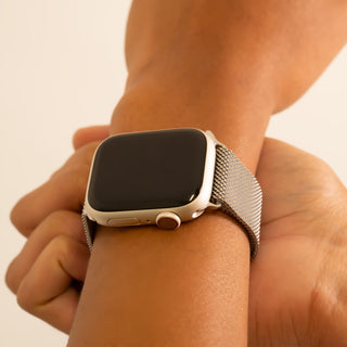 Smartwatch with a mesh band on a wrist against a neutral background