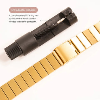 Gold watch band with black link adjuster on a white background