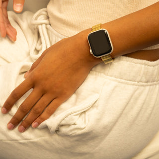 Hand wearing a gold smartwatch on a white surface