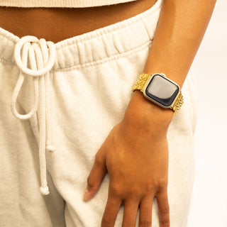 Person wearing a gold watch on a plain background